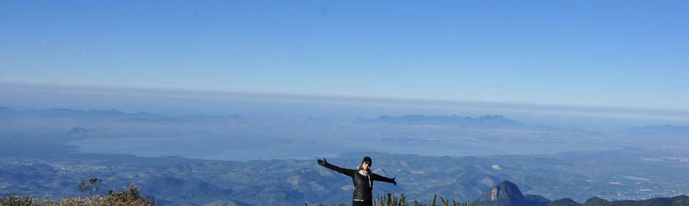 Feliz com mais um dia de céu azul no Parque Nacional da Serra dos Órgãos, no Rio de Janeiro. Ao fundo, a Baía da Guanabara
